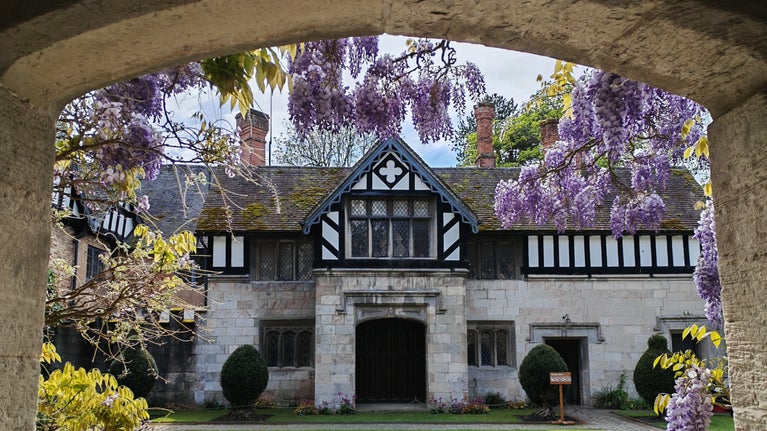A view through the archway into the courtyard at Baddesley Clinton, Warwickshire, with a curtain of wisteria blooms.
